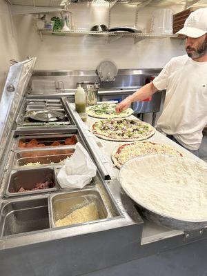 Owner making pizzas