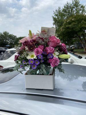 Arrangement with white daisies and other purple flowers.