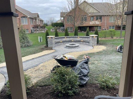 We installed a paver sidewalk connecting to a retaining sitting wall with a pillar on each side with 10 lights , round fire pit