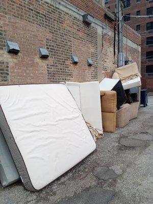 People are constantly moving in and out of this building the alleyway stays cluttered with discarded furniture.