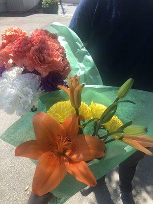 White, peach, purple carnations, orange lily and yellow spider mums.