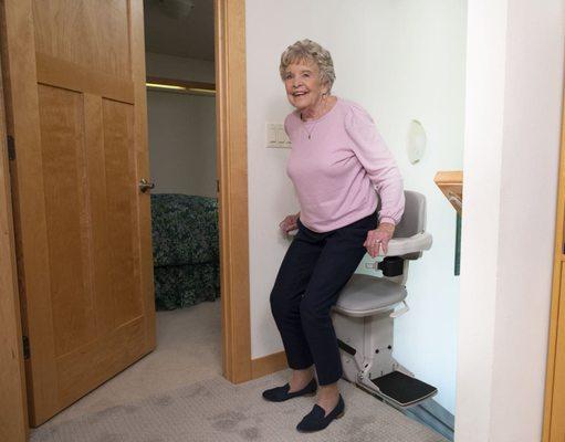 woman safely exiting new stairlift from Lifeway Mobility at top landing of stairs