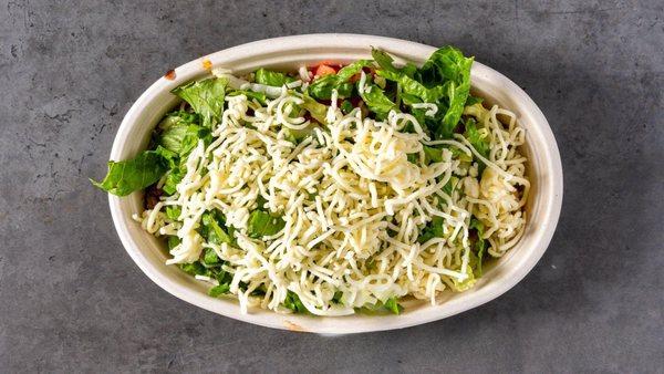 A fresh bowl loaded with crisp lettuce, juicy tomatoes, and shredded cheese--perfect for a delicious Mexican-inspired meal