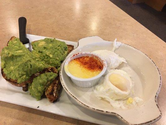 Avacado toast with poached eggs and a side of hollandaise sauce.