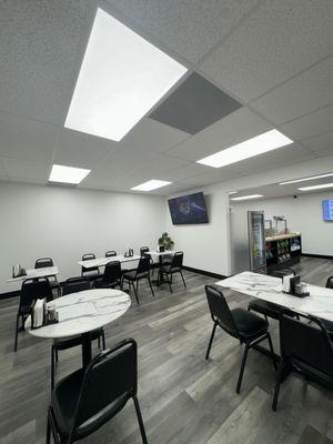 The eating area inside the restaurante features two four person tables and three two person tables.