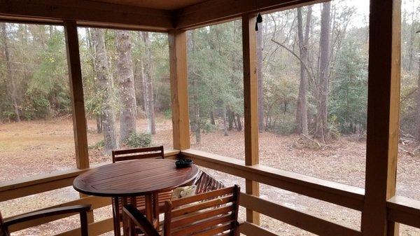 Another view of the woods from the screened-in porch. There's a table with four high chairs/stools!