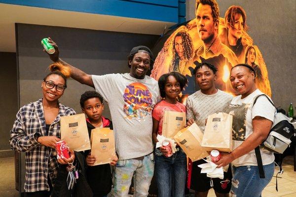 A happy family celebrating our opening day, June 5, 2022 with some free popcorn!