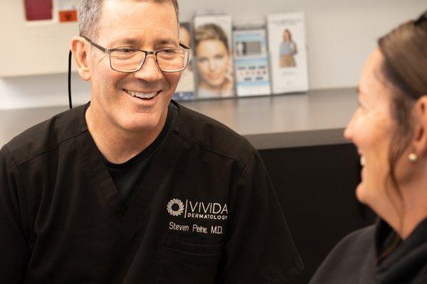 Fellowship Mohs Surgeon and Air Force Veteran, Dr. Steve Peine sharing a laugh with a patient.