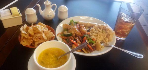 Lunch portion of Happy Family, Egg Drop Soup, mushy Fried Rice and spring roll with crispy Noodles and iced tea.