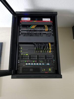 Wall-mounted I.T. rack proudly installed by TechWorks.  Notice the attention to color coded cables and organized layout.