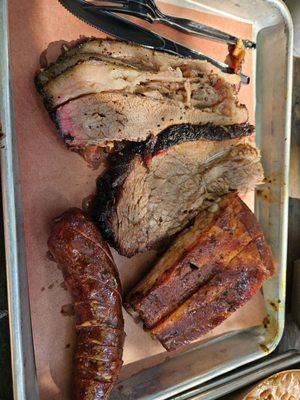 Lean brisket, fatty brisket (piece in the middle with visible bark), dry rub pork ribs, and jalapeño cheese sausage