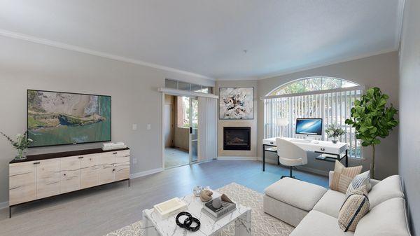 Spacious living room area featuring hardwood-style vinyl floors, a fireplace, home office, and access to a private patio/balcony.