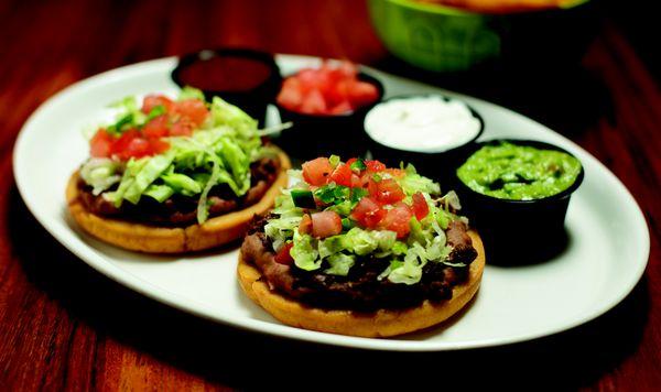 Sopes with sides of guacamole, sour cream, diced tomatoes and our signature spicy tomatillo sauce.