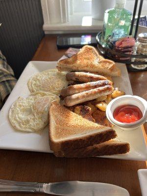 Eggs over easy, apple smoked sausage, hash browns, and white toast.