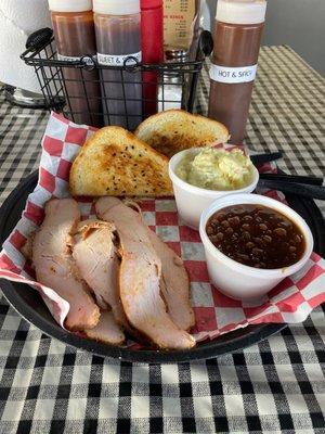 A turkey plate with baked beans and potato salad