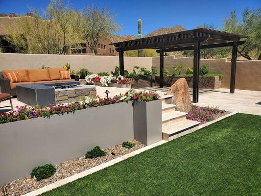 Complete backyard remodel with 2ft raised seating area, metal planters, turf, pergola and travertine.