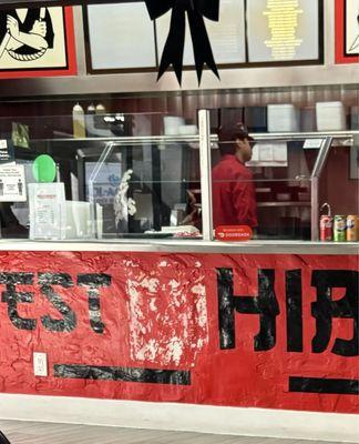 Employee playing with his hat and hair in front of the grilled