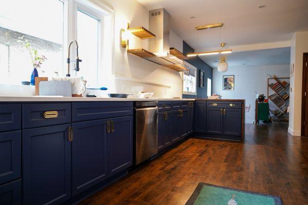 The kitchen remodel, featuring the new cabinets and drawers, open shelving, sink and stove.