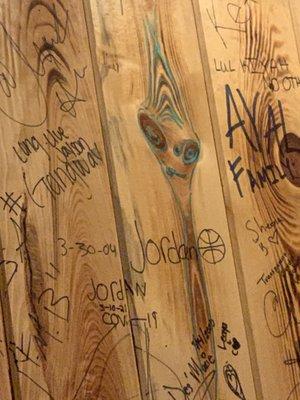 Woody the alien face along with some of the copious names and tags that are all over the walls.