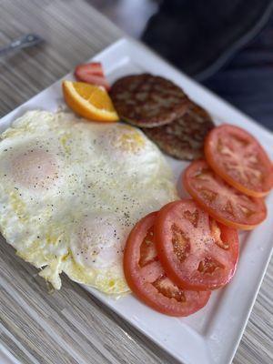 Triple egg and sausage patties plated with tomatoes.