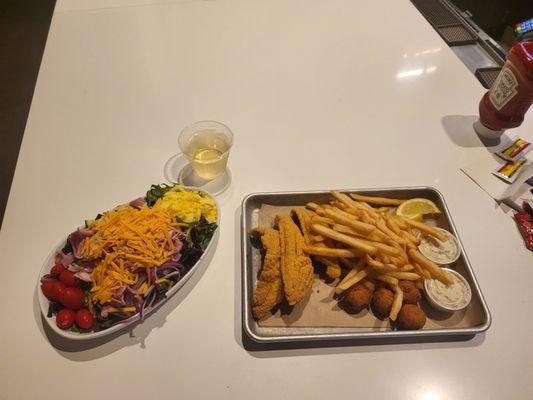 Cobb salad and fish plate with a glass of wine.