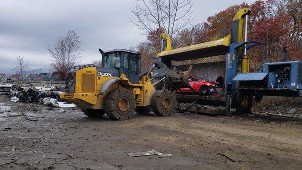 Vehicle being prepared to be completely flattened and stacked on a truck that will transport it to be recycled.