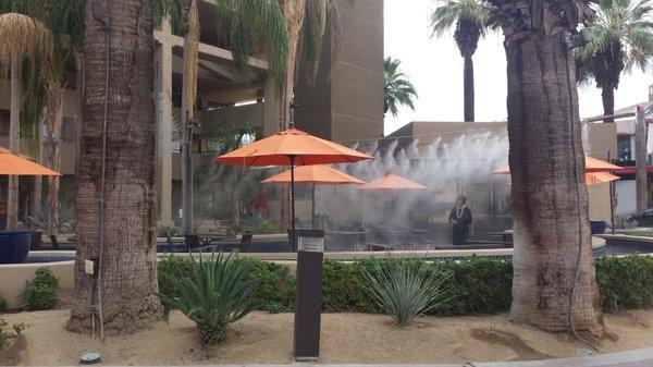 Patio dining area in Palm Springs hotel has misters suspended on line outside of hotel