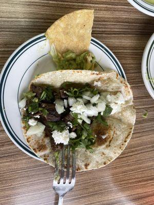 One beef fajita taco on flour, minus lettuce and tomato due to spouse's preference.