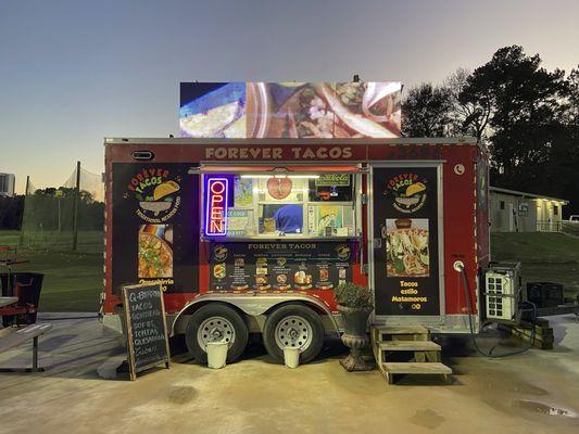 The food truck has pictures of the food (some prices) and an advertising screen on the roof.