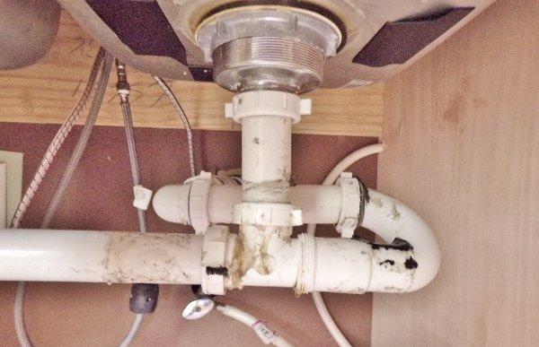 Improperly installed drainage piping under the kitchen sink.