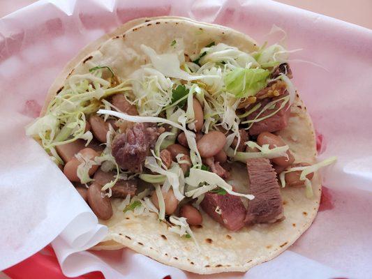 Partially eaten... So you can see what's in it. Lengua taco. Cabbage, pinto beans, cilantro, onion, but on lengua no tomato unless you ask!