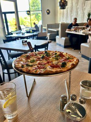 Vegetarian pizza served on a stand so the bottom can cool off.