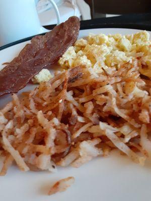 Scrambled eggs with soggy cold hash browns and bacon