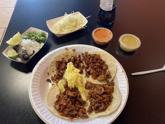 Tacos al pastor.  They have a side bar with onions, cabbage, cilantro, roasted jalapeños, limes, and two different sauces.