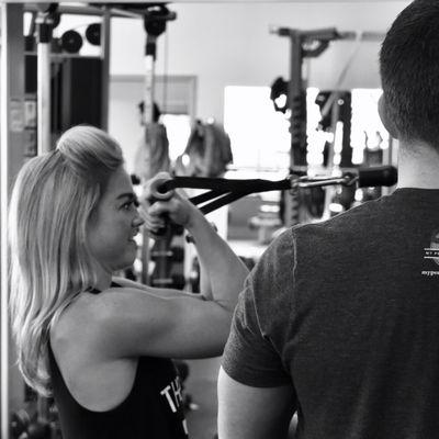 Trainer Matthew Perry working with a client on a cable bicep curl.