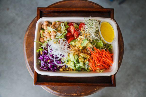 Melrose bowl with chickpeas, tomatoes, sprouts, red cabbage, cucumber, shredded carrots and our Coconut Tumeric Dressing