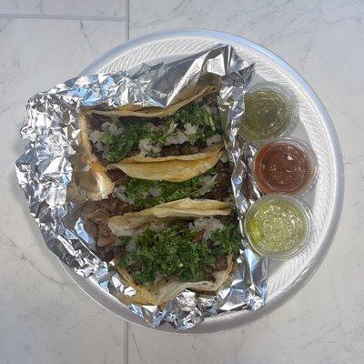 Tacos de carné asada con Rico cilantro y cebolla y salsa verde y rojo.