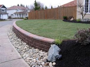 Installed a beautiful block wall w/ cap that is at the perfect height to sit on. Finished the yard off with a new sod lawn and planted beds.