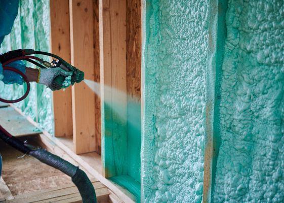 Spray foam insulation contractors installing wall insulation on a wall of a new home build.