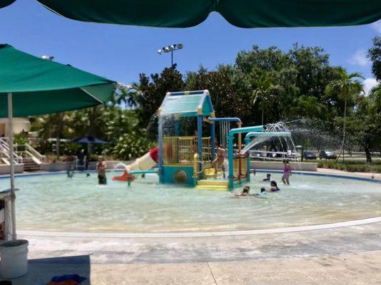 View of the zero entry splash playground from the picnic tables/umbrella