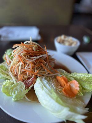 Papaya Salad (Som Tum) served with pork rinds and lettuce leaves.