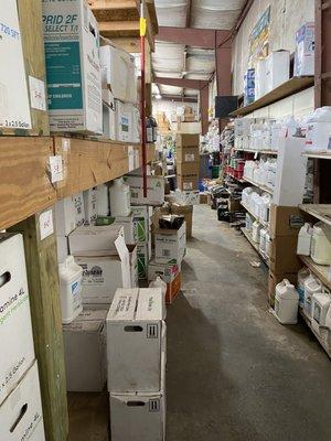 Only part of store with shelves; the rest is open warehouse of pallets loaded with bags of products.