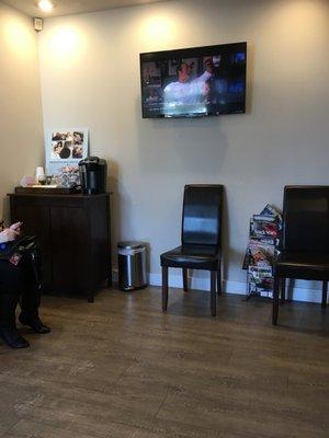 Waiting room with coffee, tv, and some comfy chairs