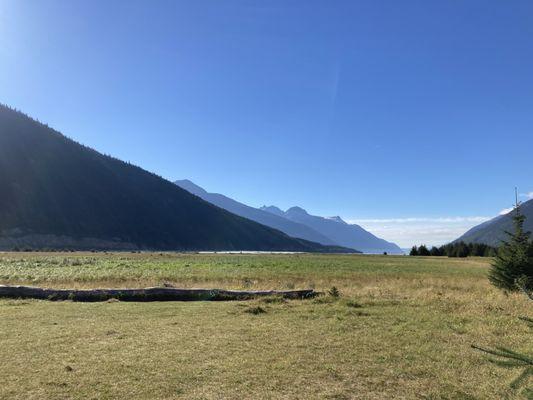 An unbelievable view from the end of a fjord, looking out to sea where jagged mountains strut about under a blue sky.