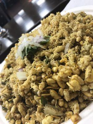 Puffed rice, crispy chickpea noodles, veggies, sauces and garnishes are the delicious ingredients in this lovely snack called Bhel Poori.