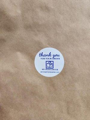 Paper bag with a white sticker with blue letters saying "thank you for your order, my hub center" then listing "www.myhubcenter.com