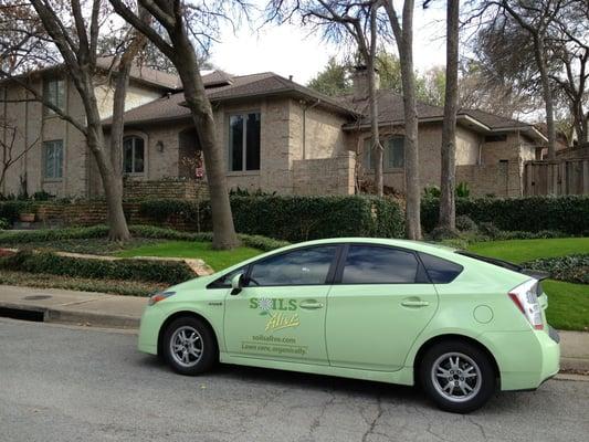 Hybrid service car in front of a beautiful organic yard.