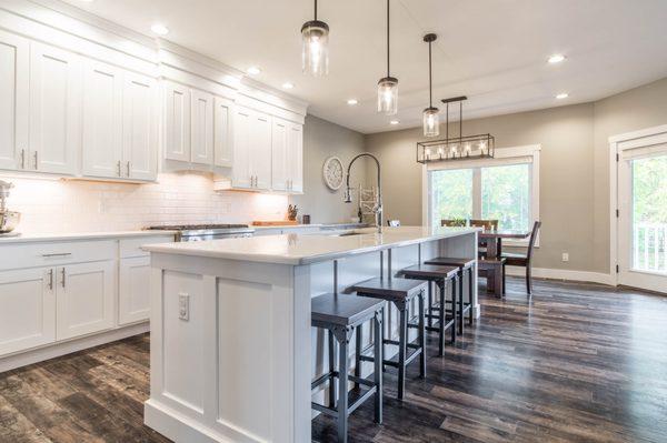 modern kitchen with white quartz island, breakfast bar, hanging pendant lights, tile backsplash and dining area