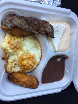 Eggs, cheese, refried beans, plantain, meat, and 2 corn tortillas.