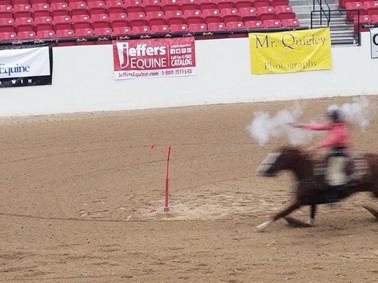 Cowgirl shooting a balloon while riding